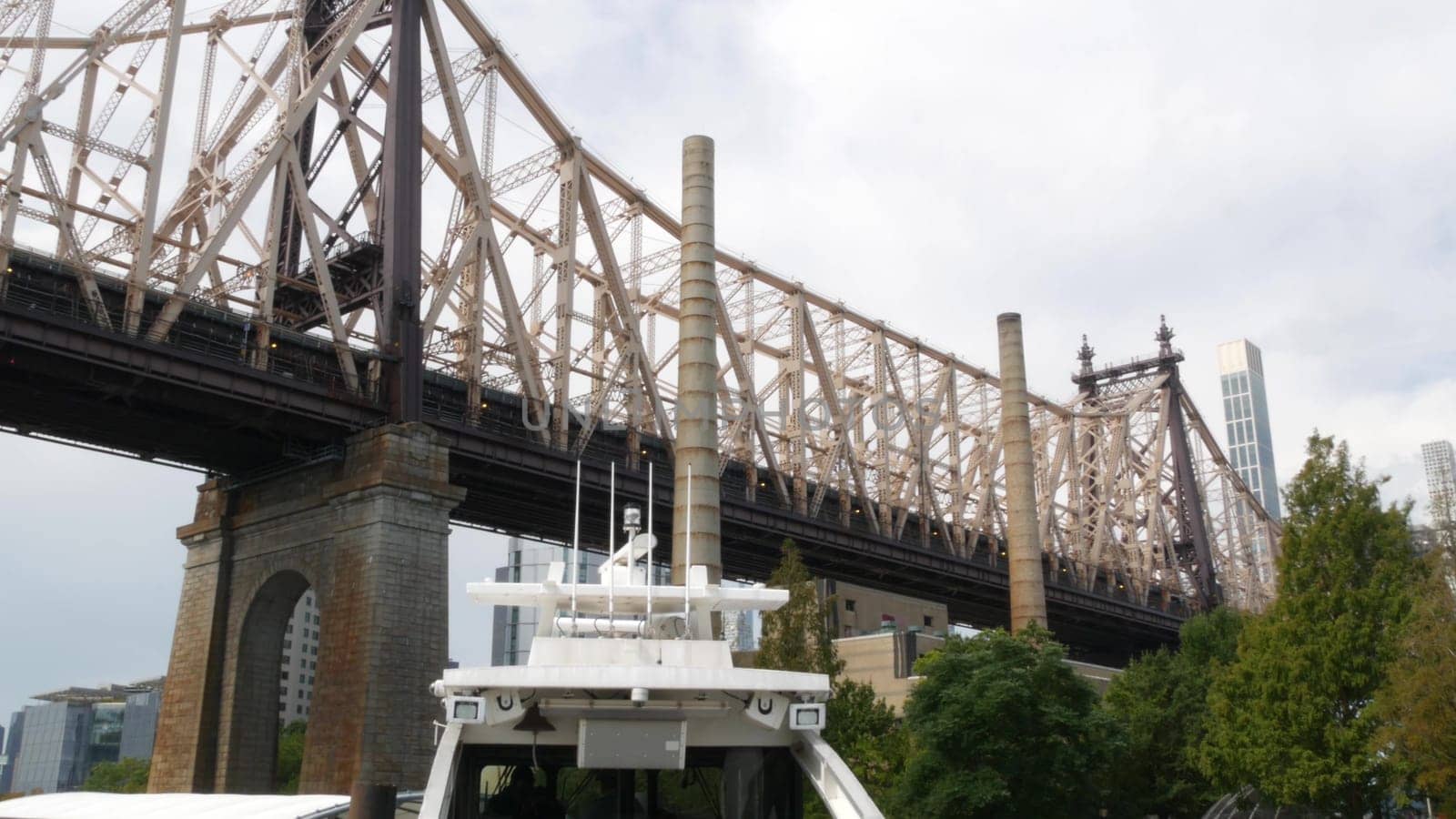 New York City, United States - 12 Sept 2023: Queensboro bridge to Queens, from ferry boat. Manhattan midtown from ferryboat. East river waterfront, riverfront architecture. Pier on Roosevelt Island.