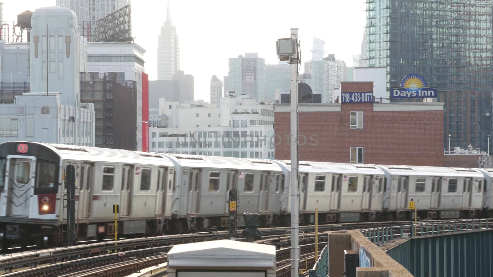New York City, United States - 2 Sept 2023: Subway station. Metro train public transportation platform. Elevated outdoor railway, Queens passenger railroad traffic, Long Island. Empire State building.