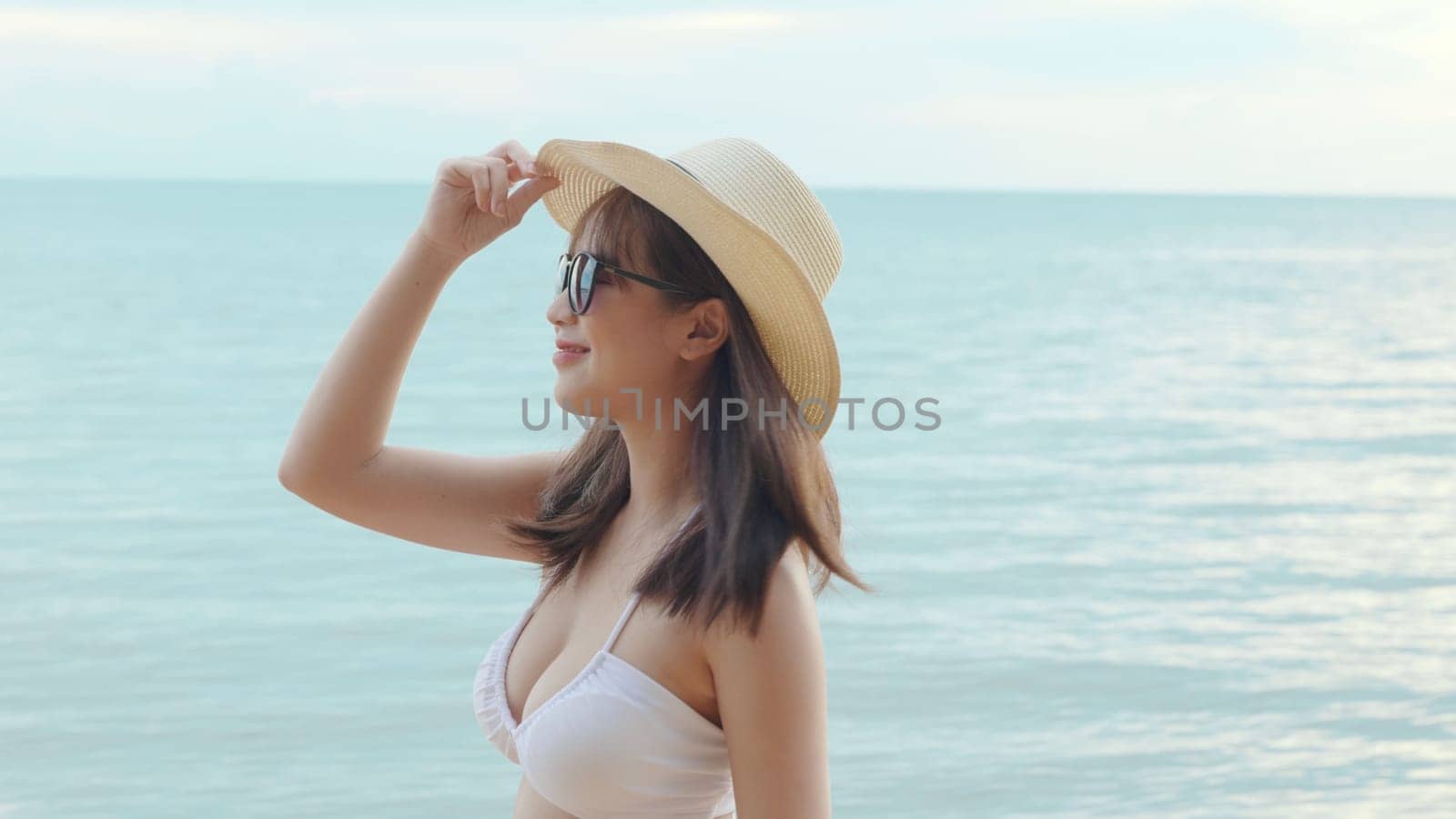Beautiful Asian woman wear sungrass and hat turning back to looking camera and smiling at beach, Portrait of happy female in bikini having fun laughing on tropical in summer holiday