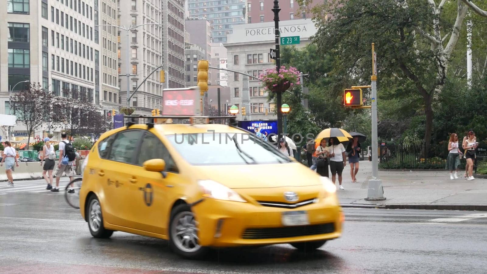 New York City, United States - 8 Sept 2023: Manhattan Midtown Broadway, 23 street, 5 avenue crossroad intersection. Madison Square Park by Flatiron Building, USA. People, subway and yellow taxi. Rain.