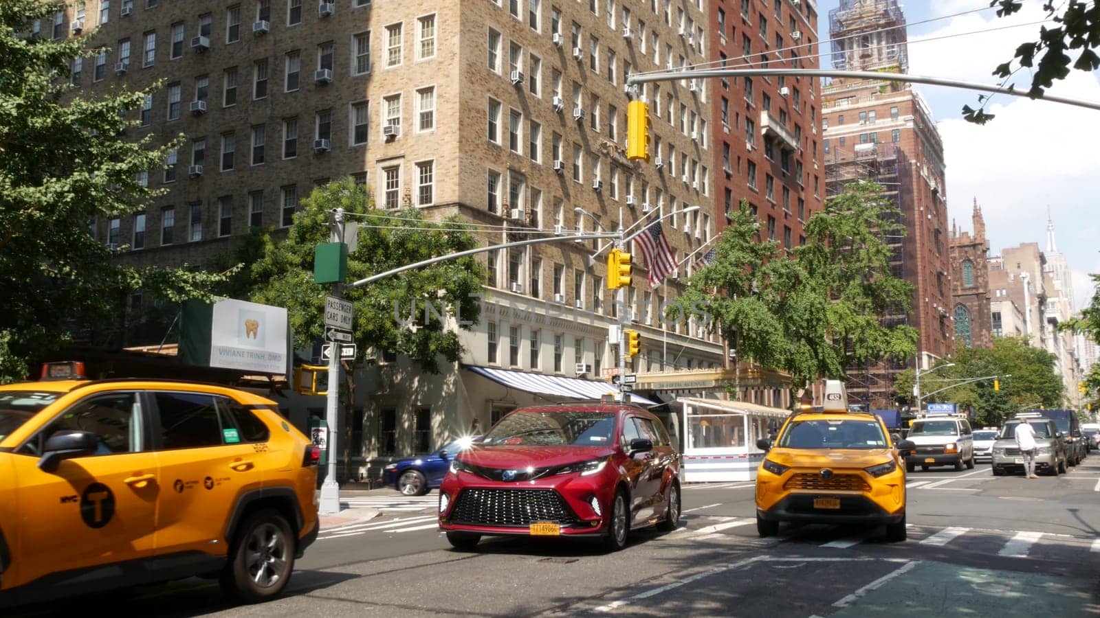 New York City, United States - 8 Sept 2023: Manhattan Greenwich Village street, 5th, Fifth 5 avenue. American urban road car traffic, people. Yellow taxi cab in USA. Empire State building and Forbes.