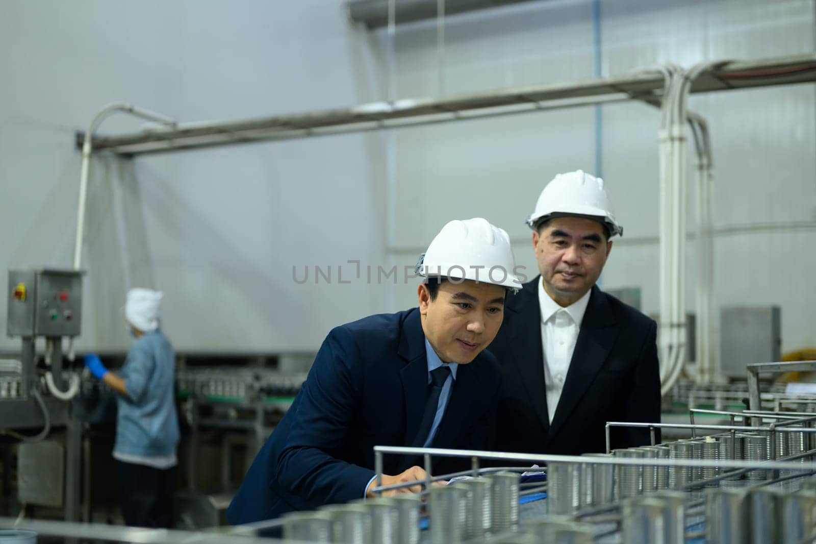 Two factory executives discussing operations inside a food manufacturing facility.