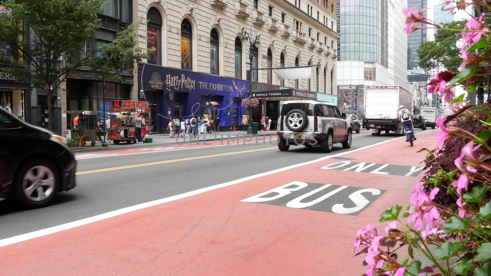 New York City, United States - 29 Aug 2023: Manhattan Midtown 34 street, near Herald Square, Broadway, 6 avenue. Urban road car traffic. Red bus lane for USA public transport. Yellow taxi cab, people.