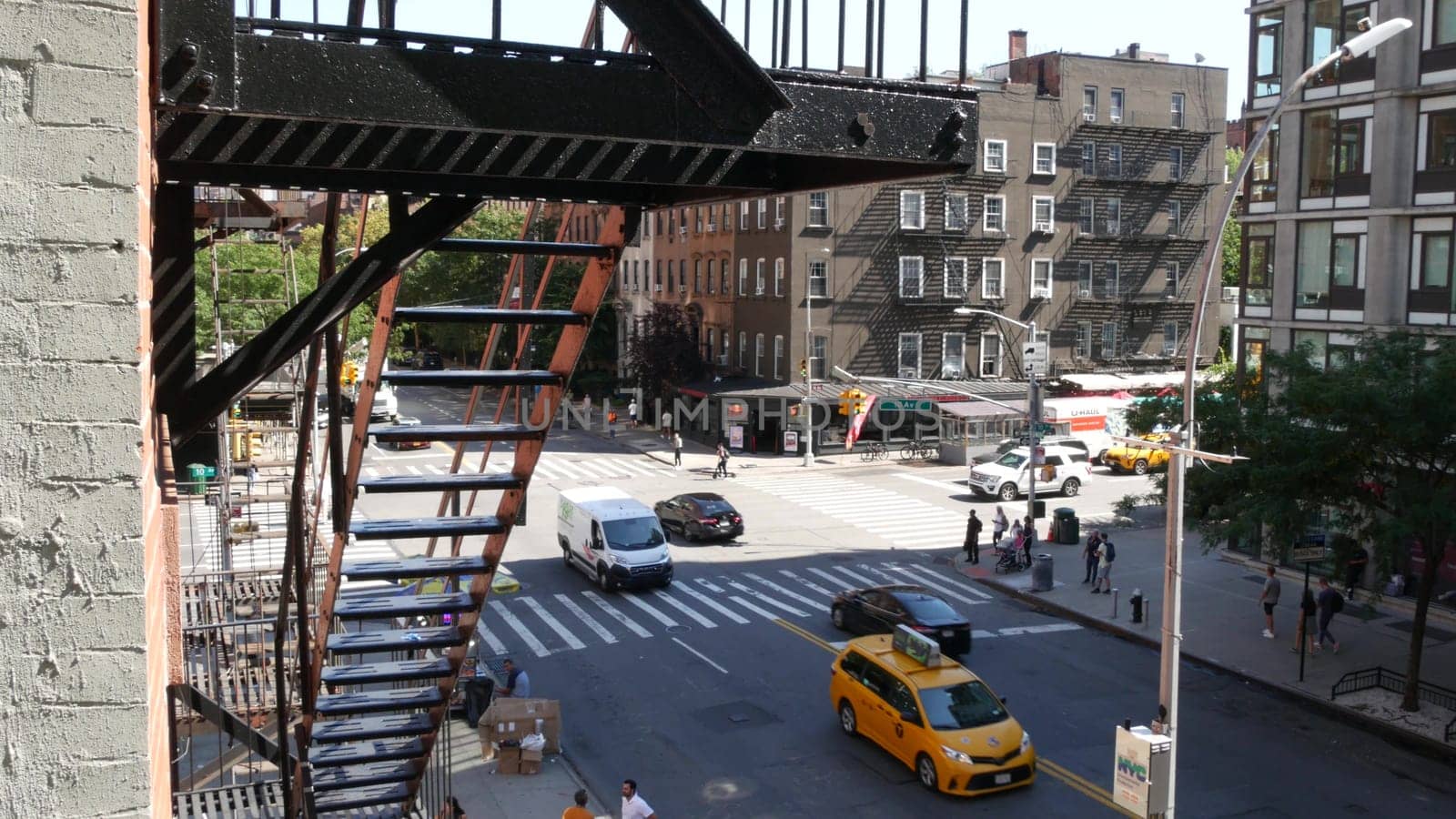 New York City, United States - 1 Sept 2023: Building architecture. Urban residential house exterior, brick facade. Fire escape ladder. Chelsea high line, 10 avenue. Street crossroad. Yellow taxi cab.