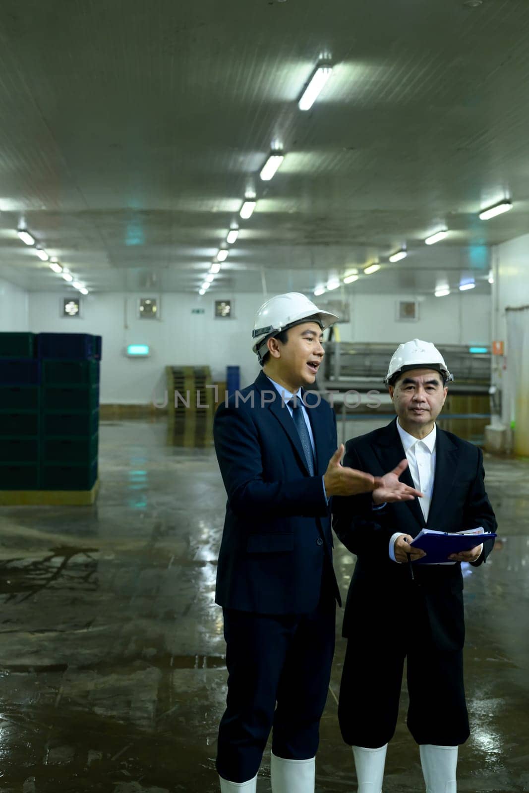 Two factory executives discussing operations inside a food manufacturing facility.