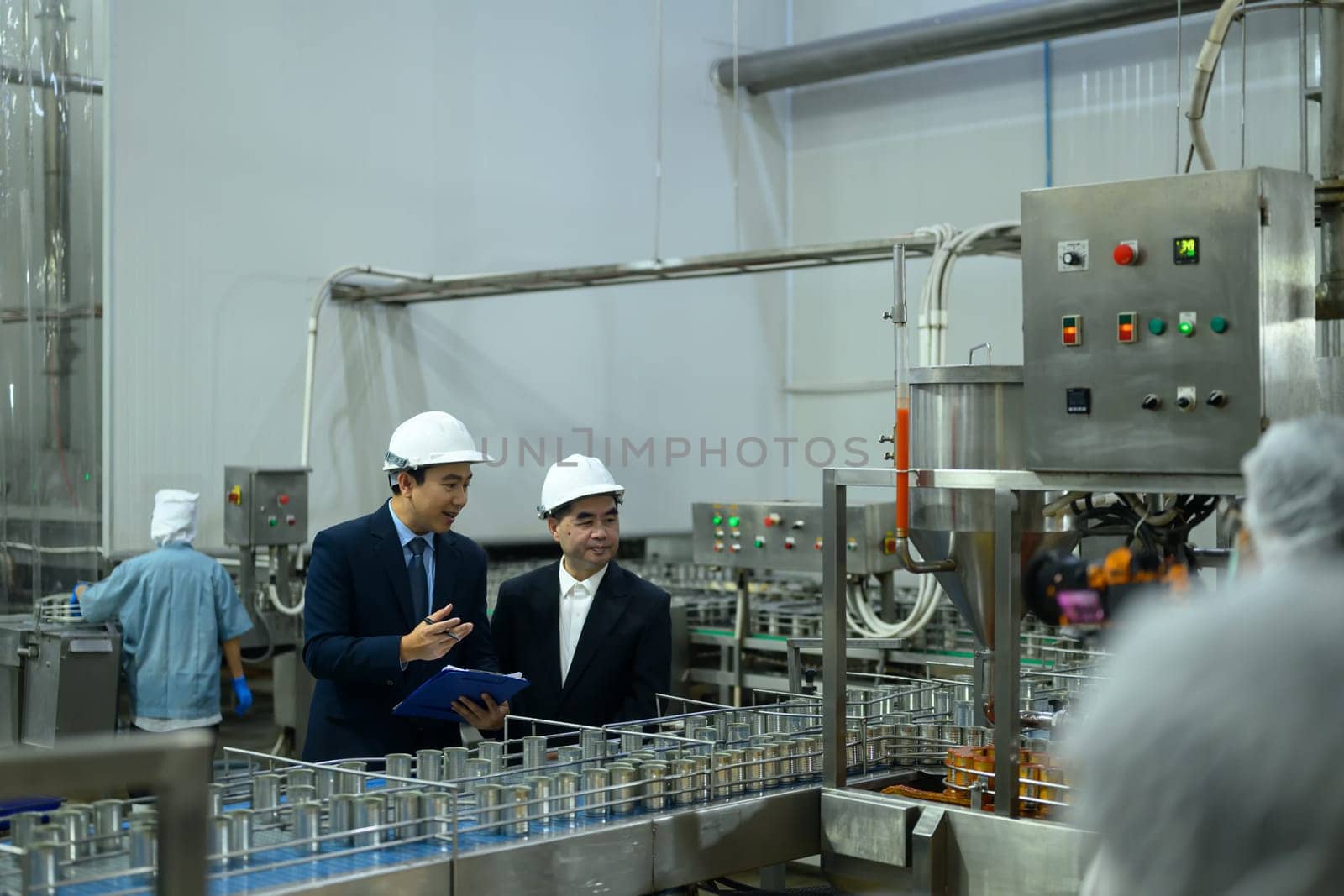 Two factory executives discussing operations inside a food manufacturing facility.