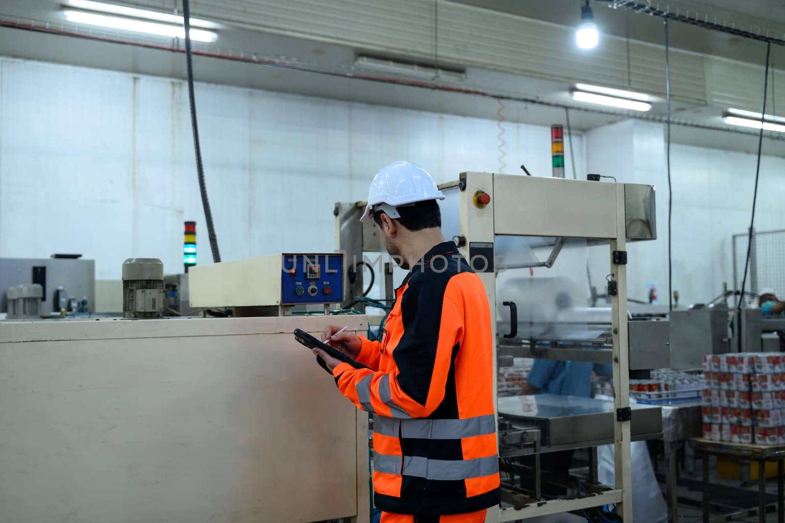 Factory technician monitoring food processing machinery in an industrial facility.