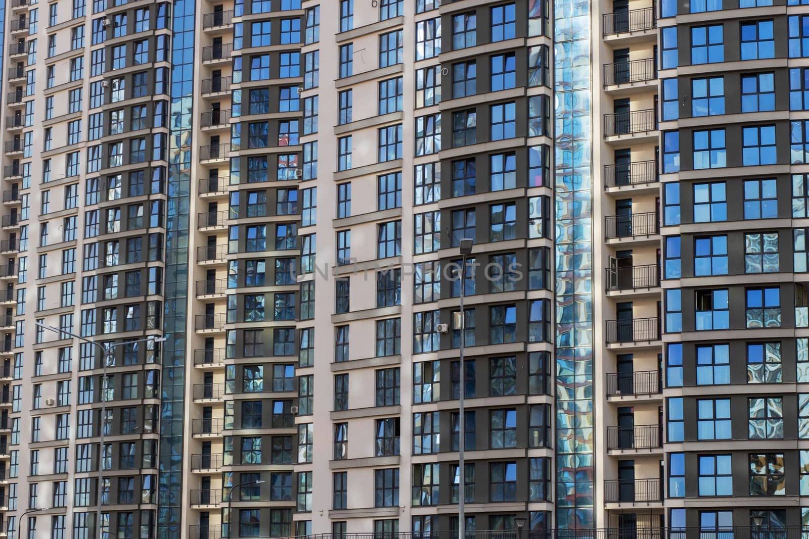A long row of extremely tall buildings adorned with a multitude of windows that capture the light beautifully during the day