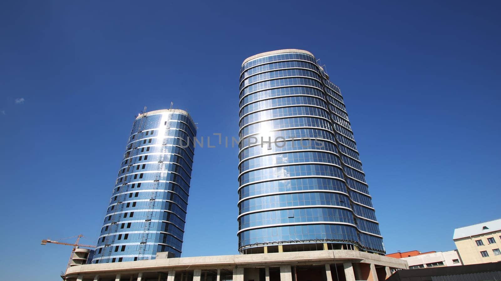 There are two extremely tall buildings standing prominently, and they are set against a beautiful blue sky that enhances their impressive stature