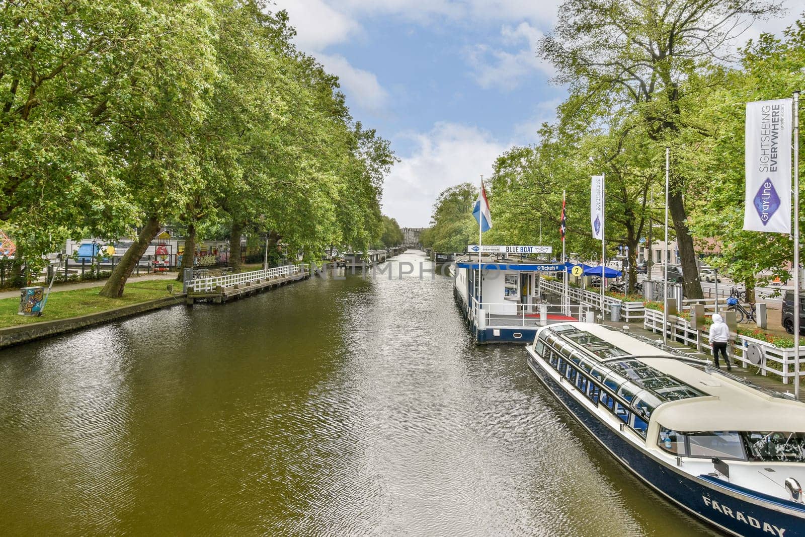 Serene canal view lined with tall trees and a boat dock, set against a bright sky. Ideal for showcasing tranquil water landscapes.