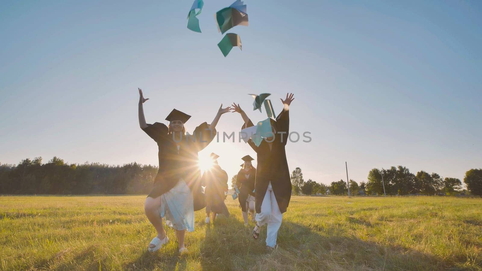 College graduates run into the sunset and throw books and notebooks up in the air