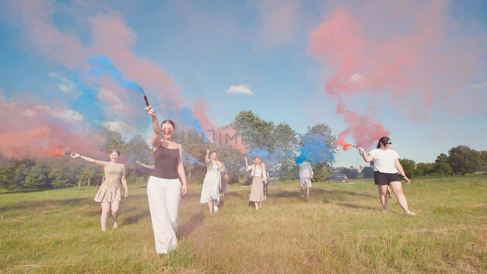 Group of teenagers walking in a field, holding colored smoke bombs, enjoying summer break and celebrating graduation