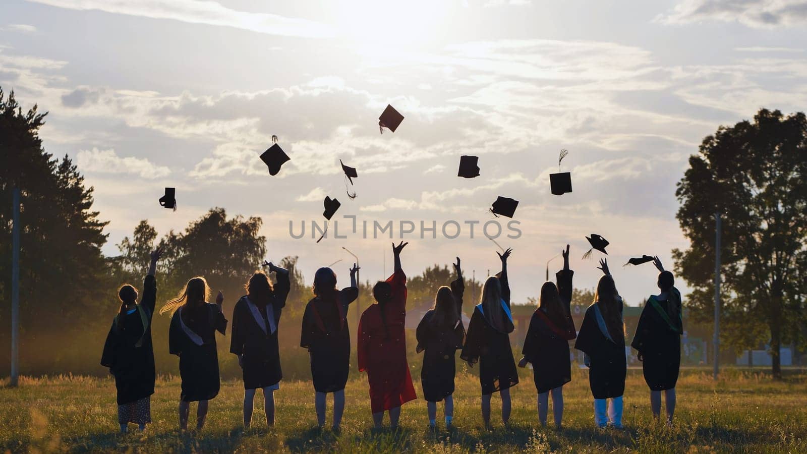 Group of graduates throwing graduation caps in the air at sunset, celebrating their academic achievement and the start of a new chapter in their lives