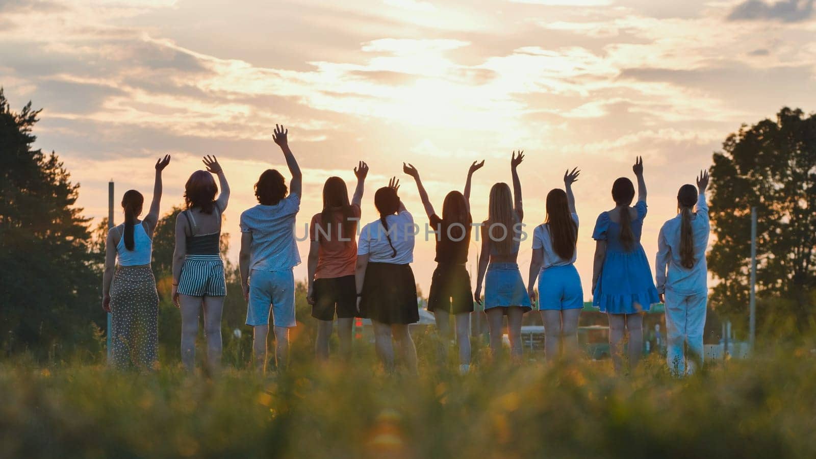 School friends waving goodbye at sunset, celebrating the joyful end of their school days together in a vibrant, grassy field