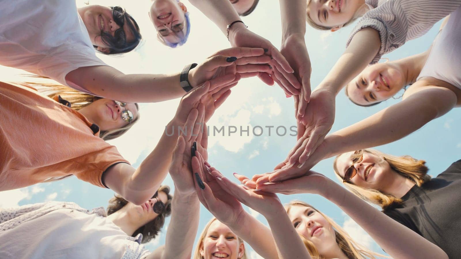 Group of students forming circle with their hands, symbolizing teamwork, friendship, and unity