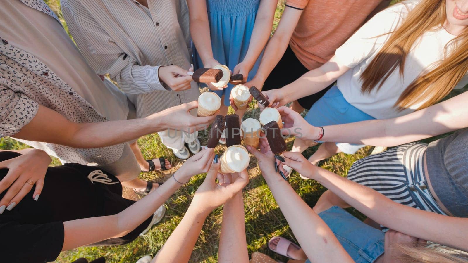 School friends having a delightful time with ice cream cones and chocolate bars on a sunny day