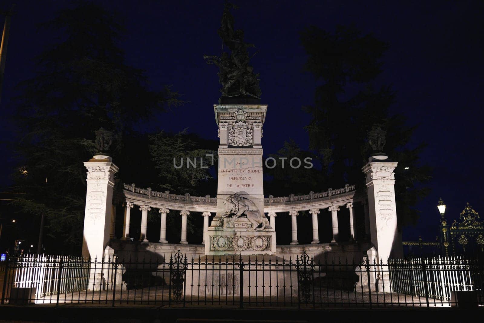 Imposing stone war memorial in Lyon, France, honoring fallen soldiers of the Rhone, captured at night with dramatic lighting.