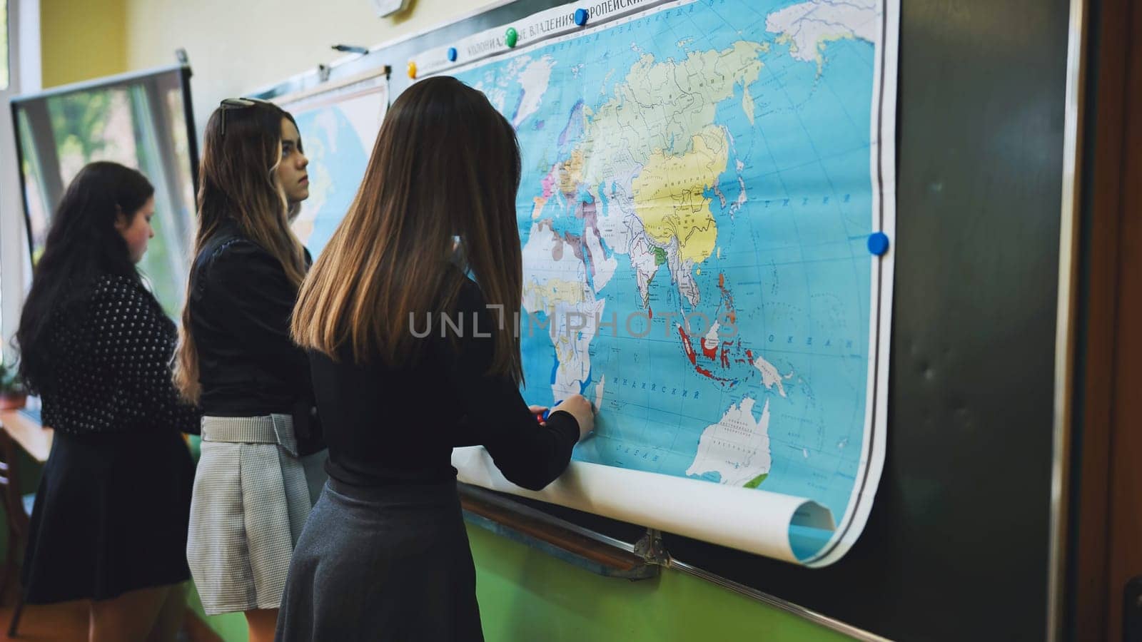 High school students actively participating in a geography class, pinning locations on a large world map
