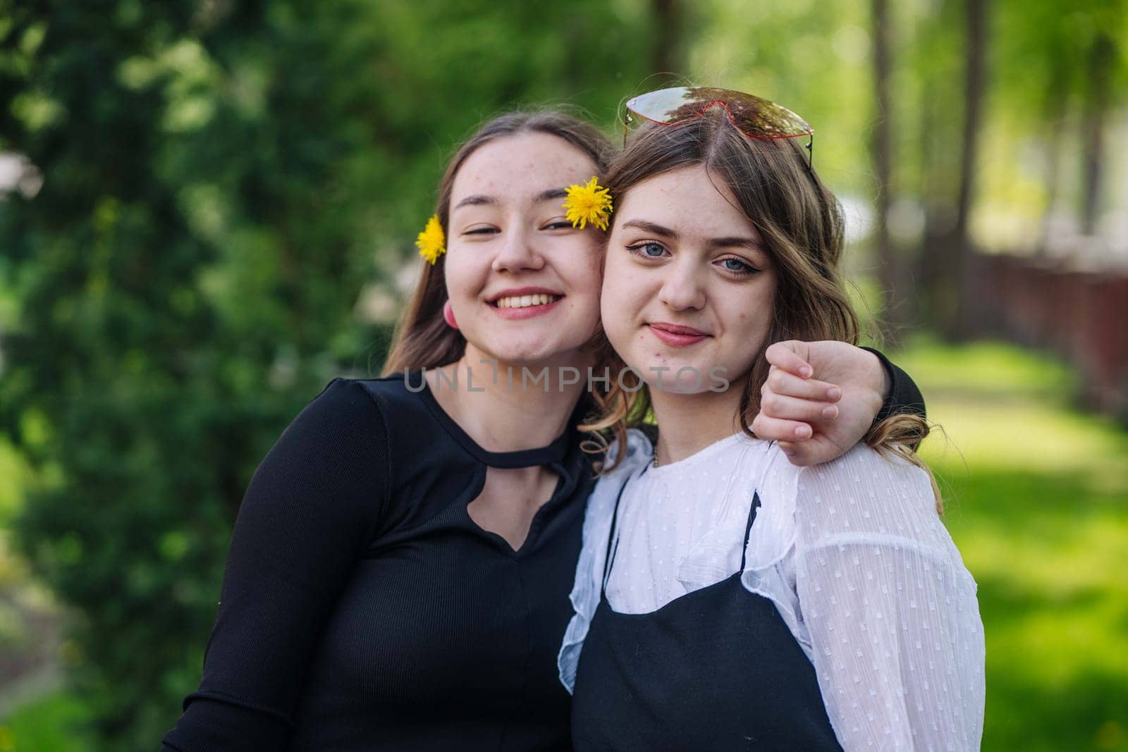 Two cheerful students hugging, enjoying their time together on a sunny day on school grounds
