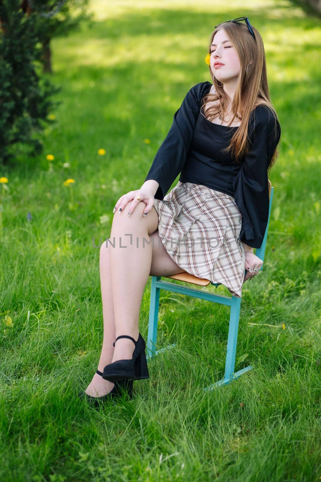 Young student sitting on a chair in a grassy outdoor setting, enjoying a moment of relaxation during a sunny school day