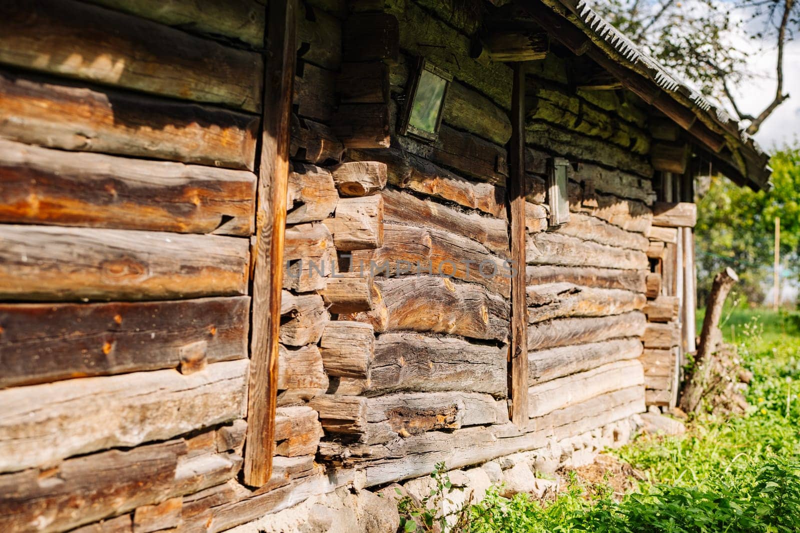 Weathered wood planks forming the wall of an old wooden house, showcasing rustic charm in a rural landscape