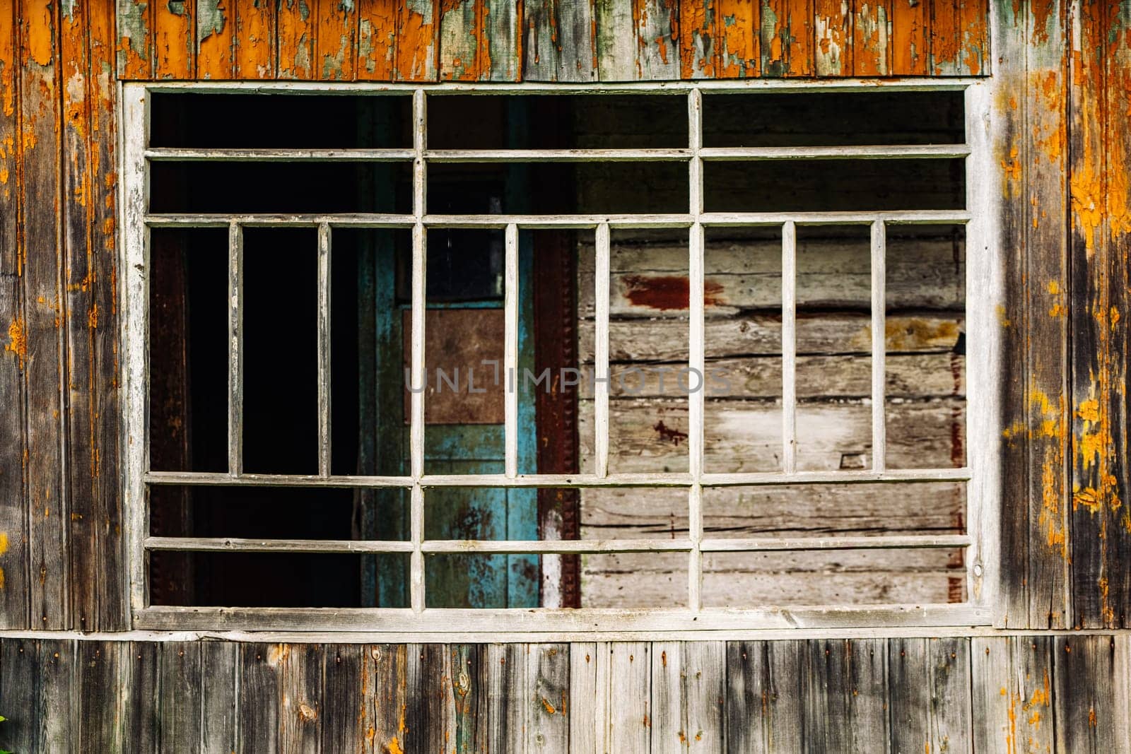 Barred window of abandoned building showing peeling paint and decay