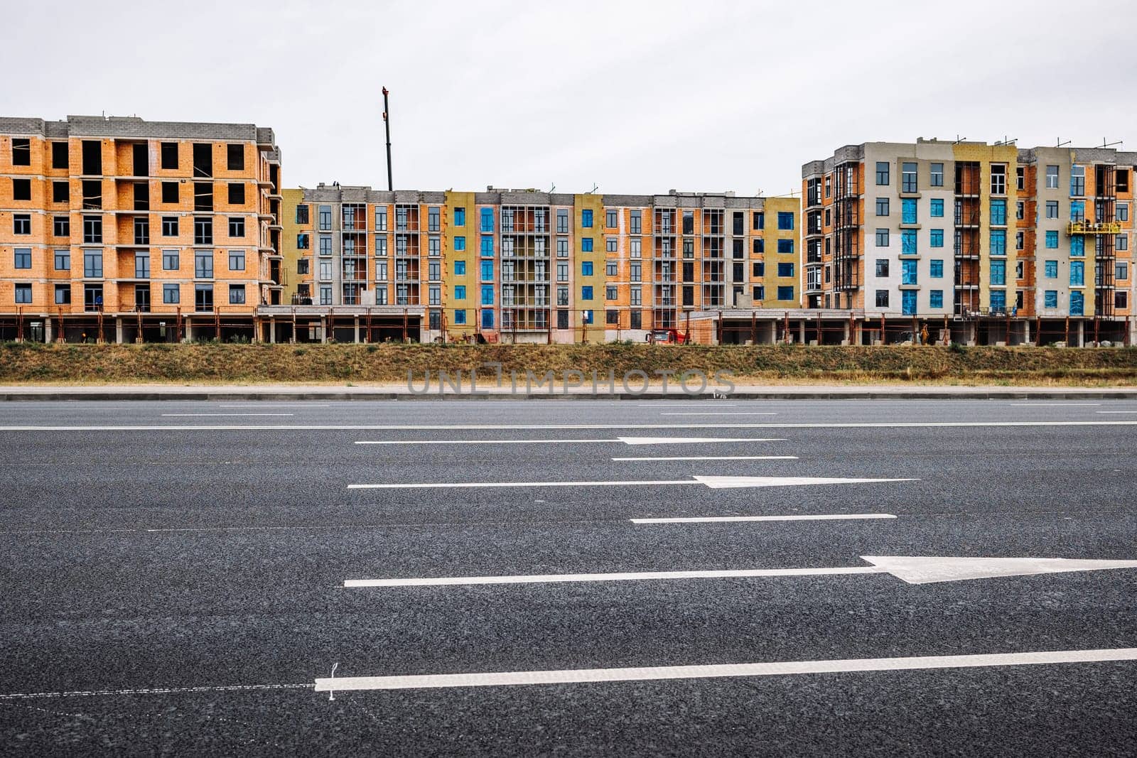 New apartment buildings under construction along a highway with turning lane markings