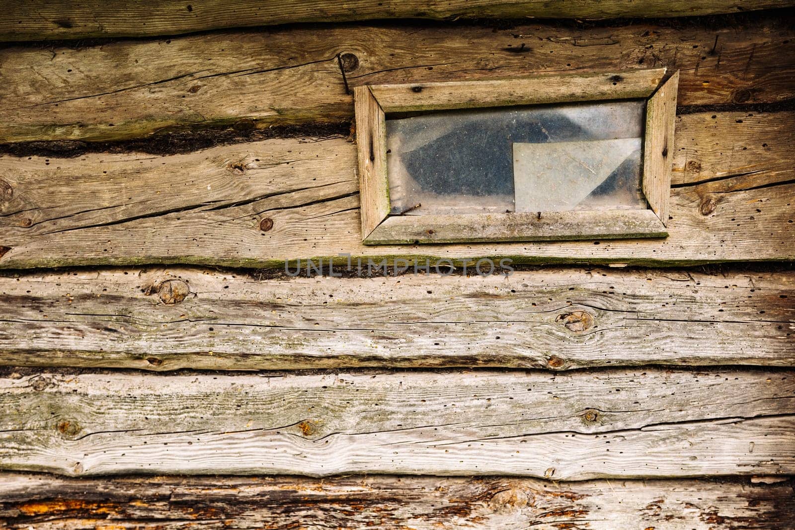 Old weathered wooden planks and a small window with broken glass are creating a rustic background