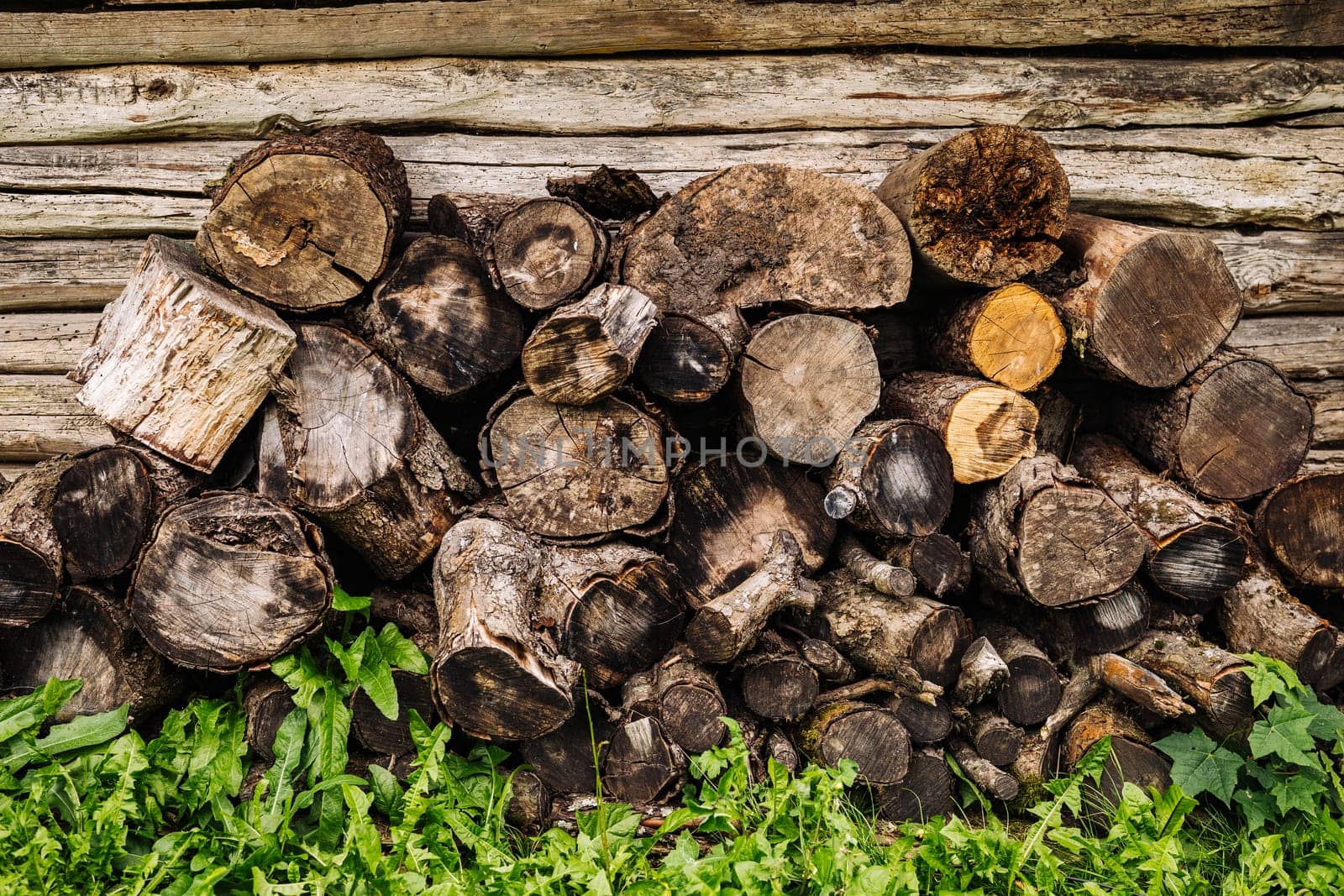 Firewood logs stacked against a wooden wall, ready for winter, providing warmth and fuel