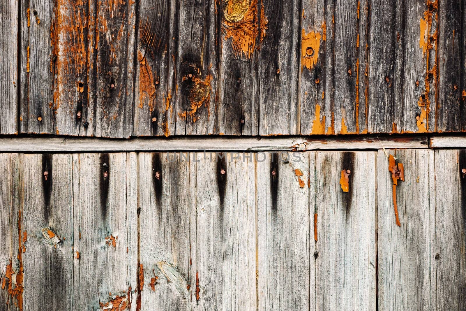 Weathered wooden planks with peeling orange paint create a rustic, textured background, ideal for design projects needing a touch of vintage charm