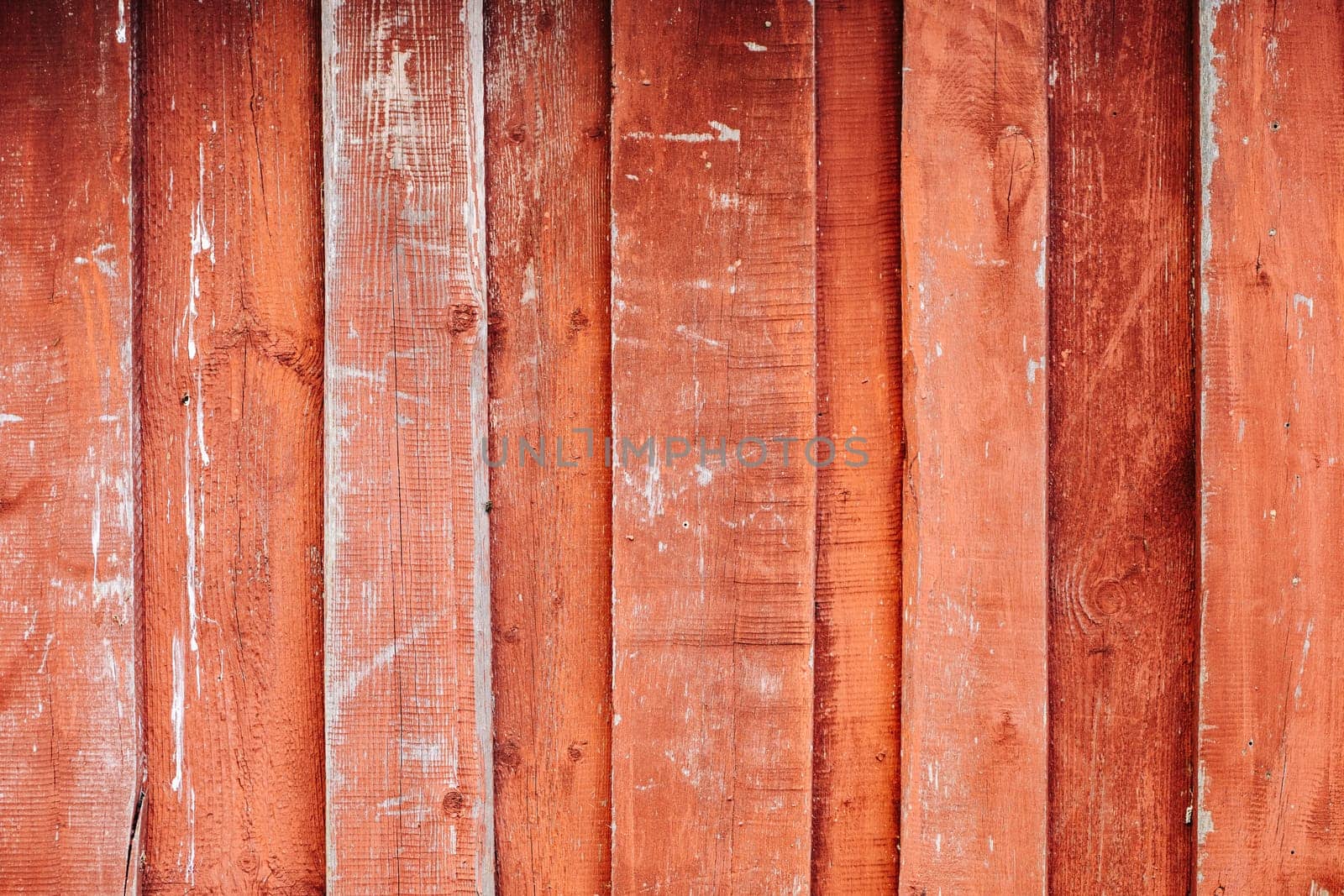 Weathered red wooden planks showing signs of age and wear, creating a rustic, textured background