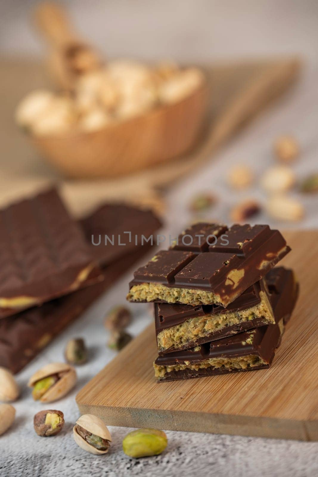 Gourmet chocolate mixed with crunchy kadaif pistachio pieces is beautifully presented on a wooden board, making a perfect treat in Dubai's culinary scene.