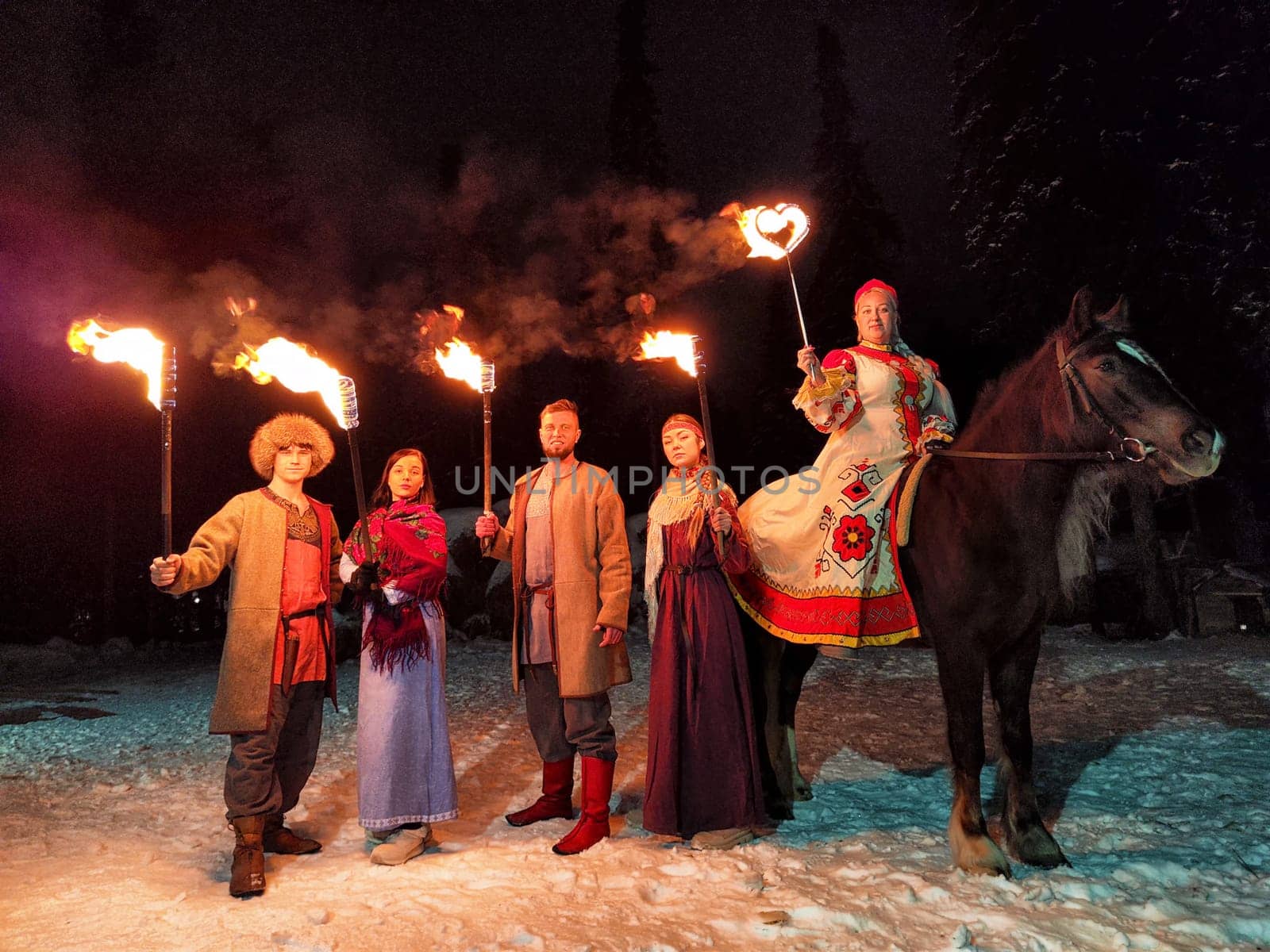 Actors in ethnic costumes perform an impressive fire show against the backdrop of a cold winter night, honoring Viking traditions.