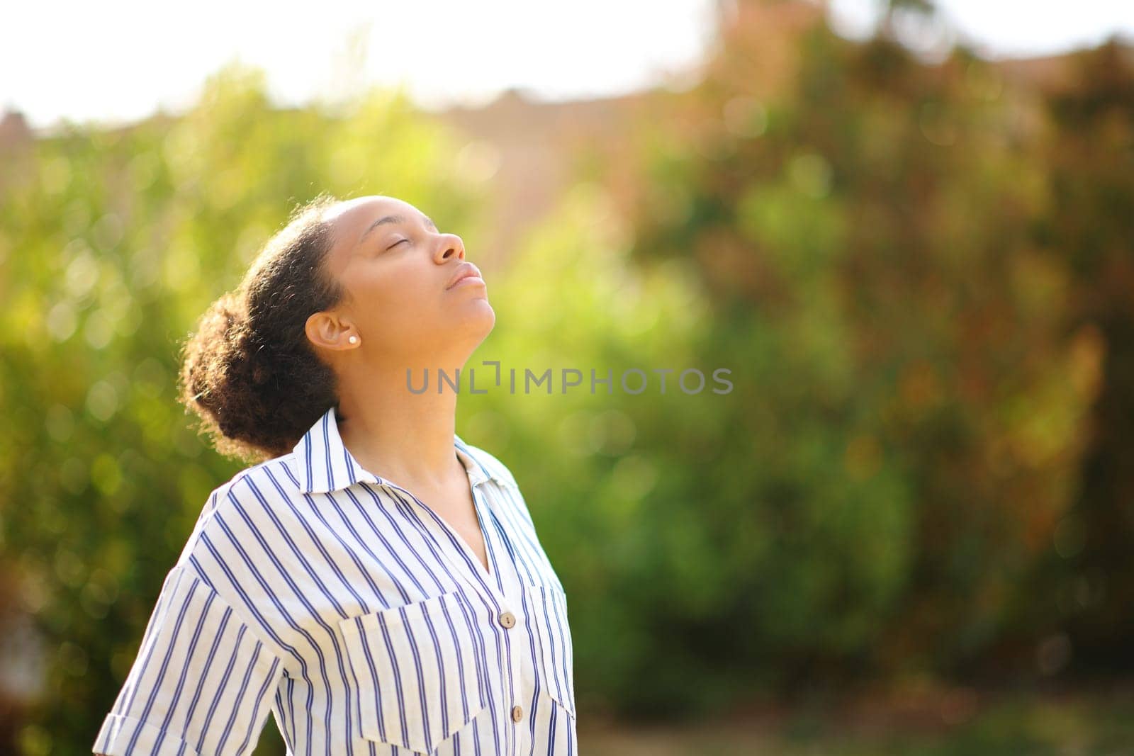 Black woman breathing fresh air standing alone in a park