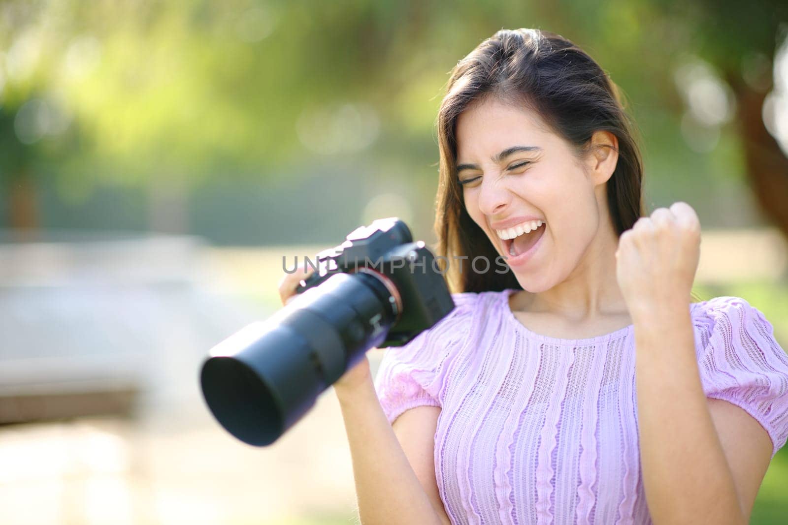 Excited photographer in a park checking results on mirrorless camera