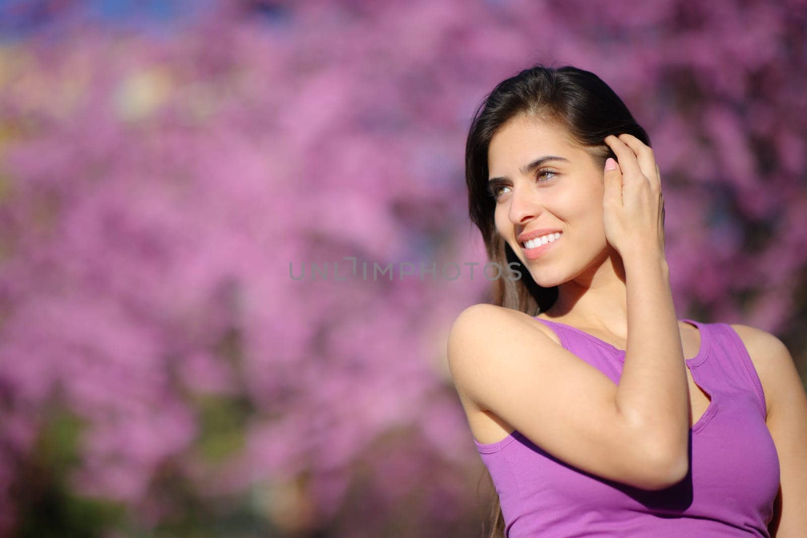 Beauty woman touching hair in a violet park looking at side