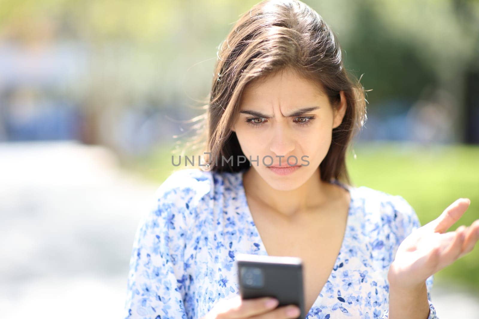 Upset woman checking phone content in the street