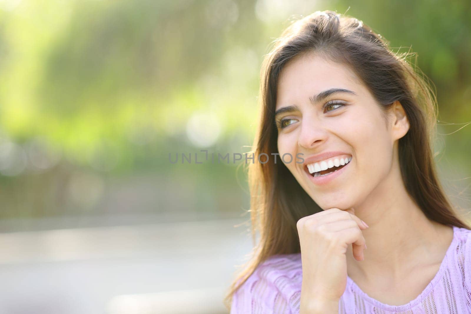 Happy woman with perfect smile looking away in a park
