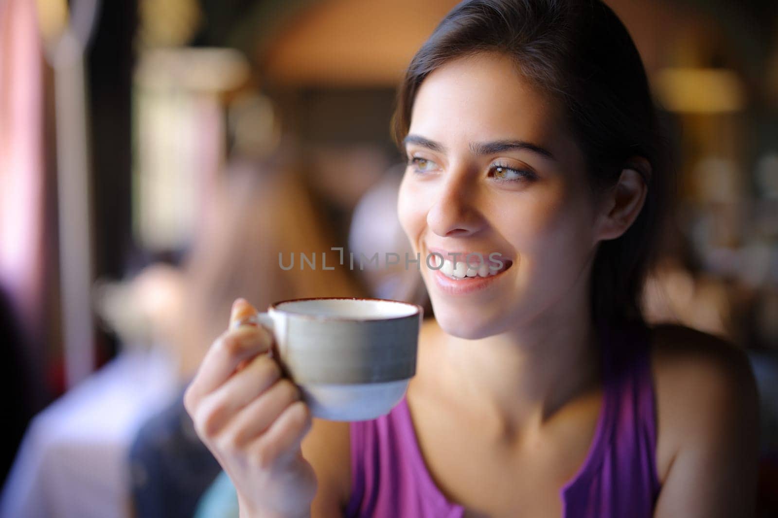Happy woman enjoying holding coffee cup in a restaurant