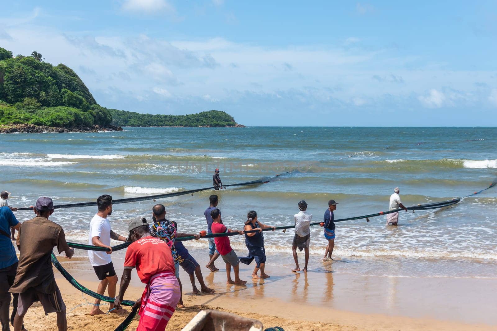 Galle, Sri Lanka - September 14 2024; Two men coming in through small surf in traditional fishing boat or 
oruwa at South Sri Lankan beach.
