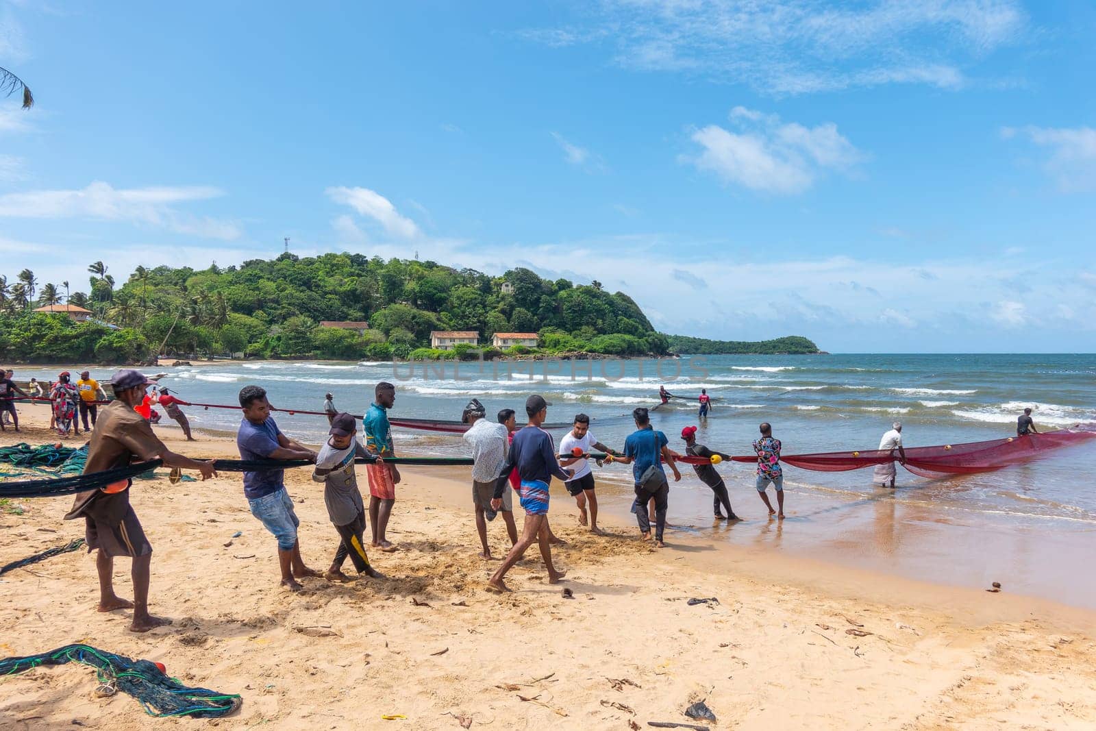Galle, Sri Lanka - September 14 2024; Two men coming in through small surf in traditional fishing boat or 
oruwa at South Sri Lankan beach.