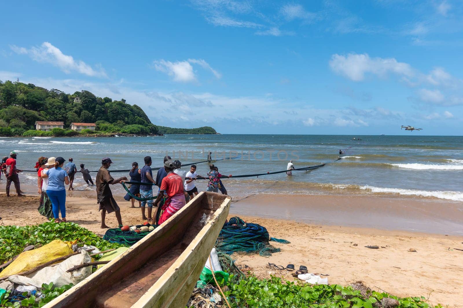 Galle, Sri Lanka - September 14 2024; Two men coming in through small surf in traditional fishing boat or 
oruwa at South Sri Lankan beach.