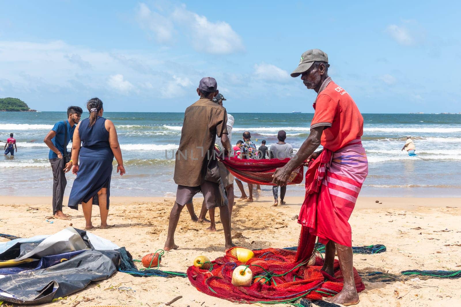 Galle, Sri Lanka - September 14 2024; Two men coming in through small surf in traditional fishing boat or 
oruwa at South Sri Lankan beach.
