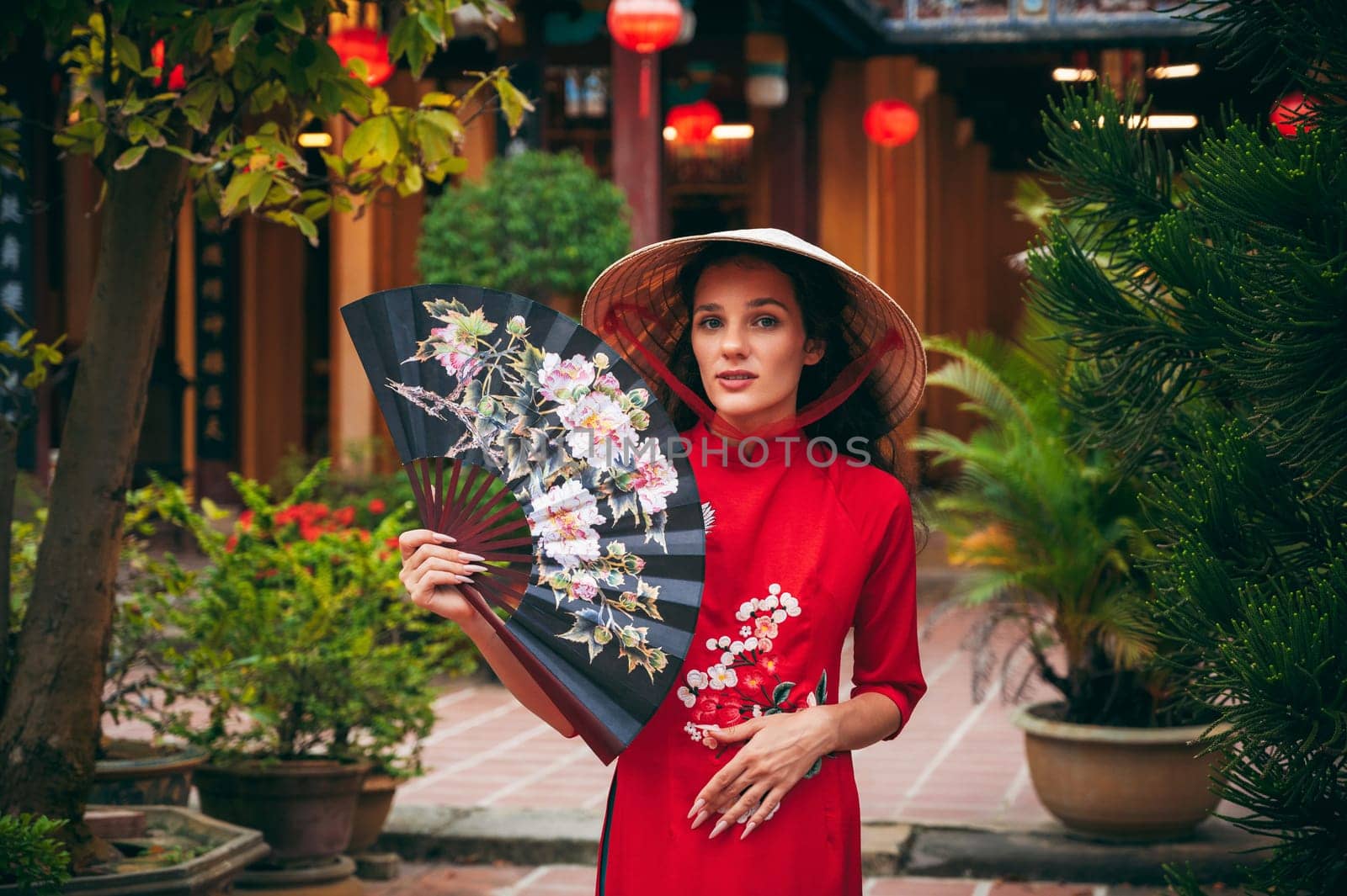 Portrait of a female tourist traveler in a Vietnamese cone hat Non La at the Hoi An pagoda in Vietnam in Asia