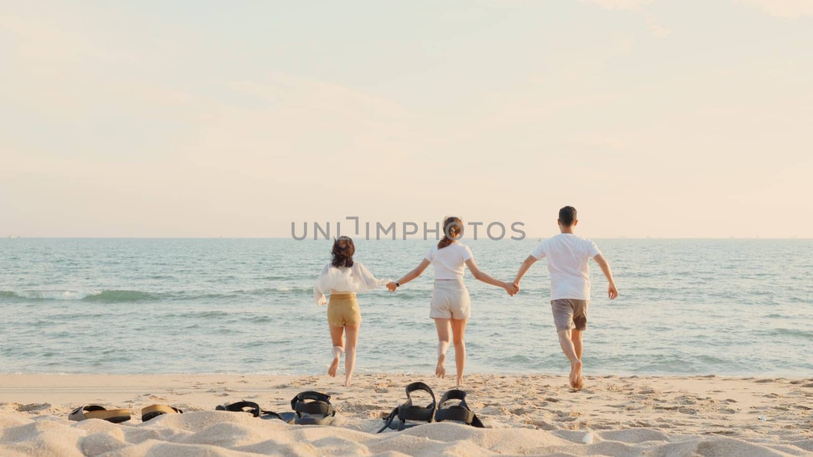 Happy friends holding hands running enjoy life funny and freedom on sand at beach together to sea in holiday vacation time at sunset, Young Asian group woman and man in summer travel, people lifestyle