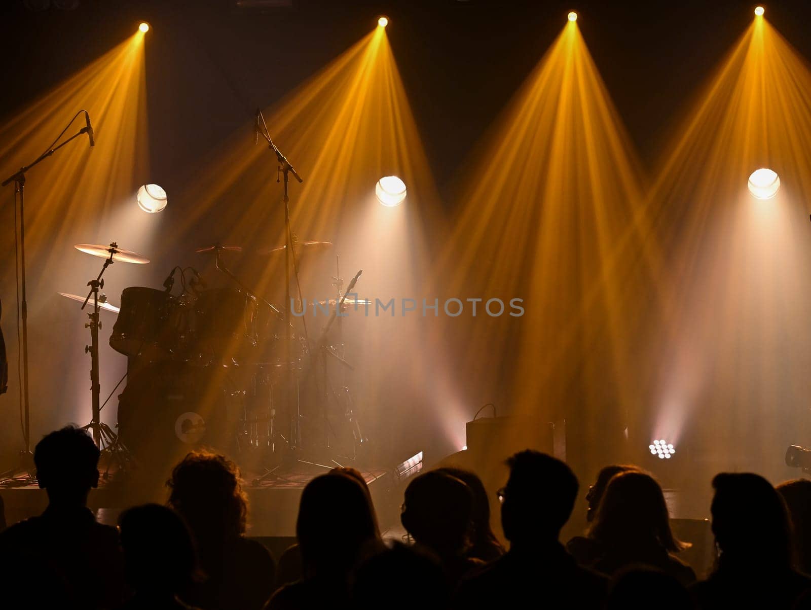 Bright lights illuminate the stage as musicians tune their instruments. A crowd gathers, eagerly anticipating a vibrant concert experience filled with energy and excitement.
