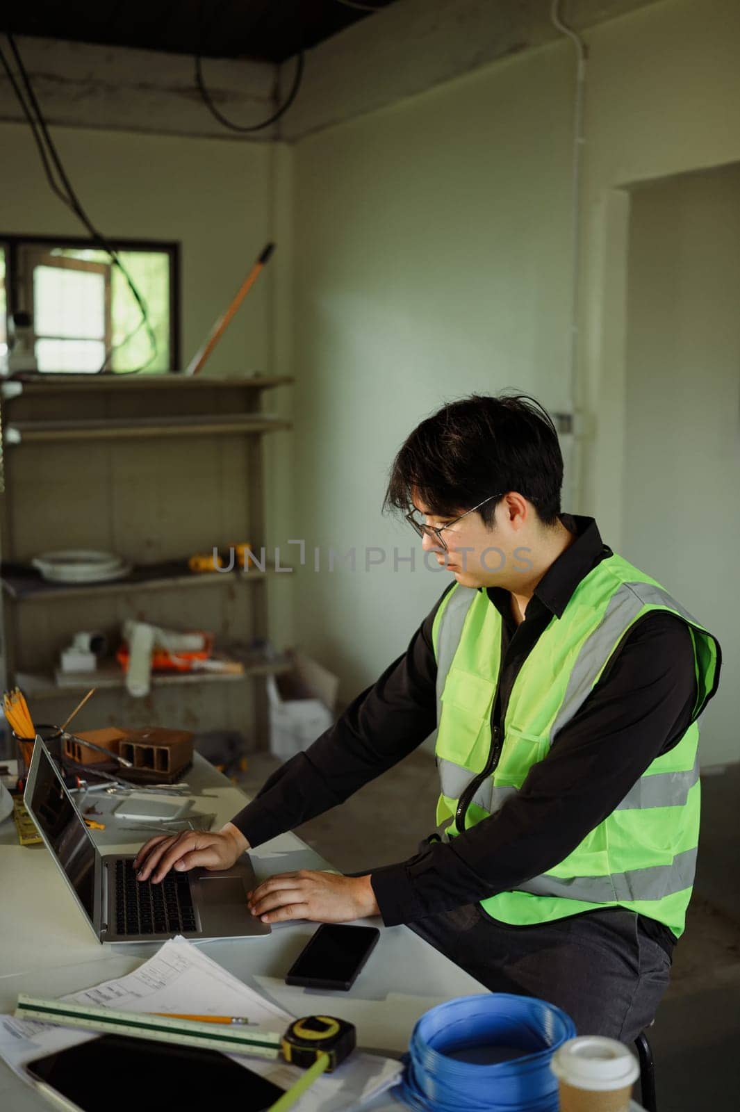 Engineer using laptop to review plans and manage site progress in a home renovation.