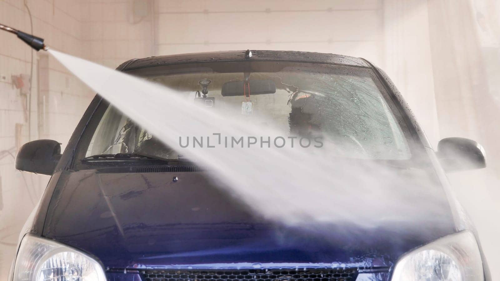 High pressure water jet cleaning car in professional car wash station