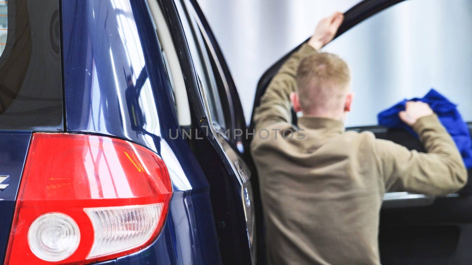 Professional car wash worker cleaning car interior with microfiber cloth, focusing on car detailing and hygiene