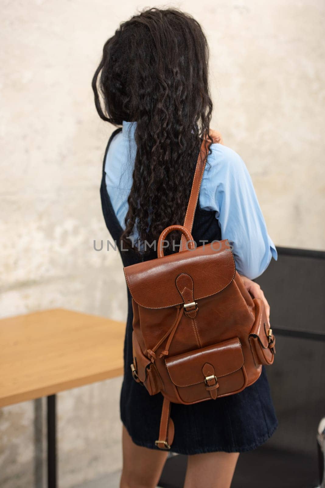 A fashionable model confidently showcasing a modern outfit while sporting a brown backpack accessory